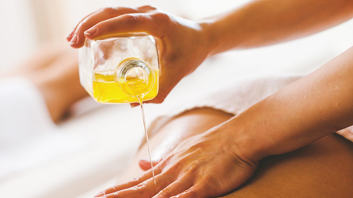 Woman pouring massage oil on spa client
